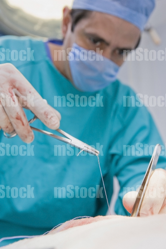 Cirujano Médico cosiendo en cirugia 4
