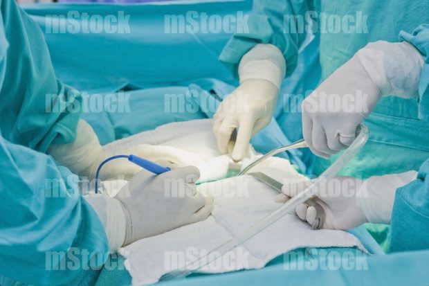 Doctor en cirugía con manguera de drene