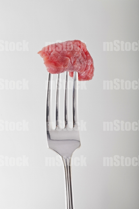 Bocado de res crudo en tenedor