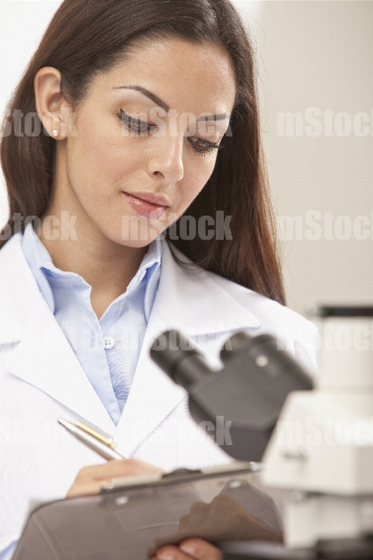 Doctora tomando notas de Microscopio