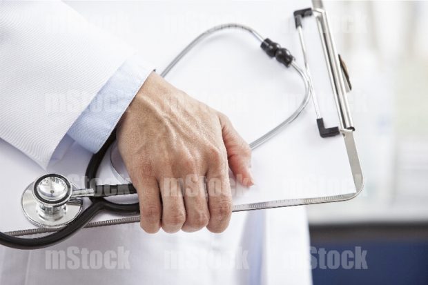 Mano de Doctora con tabla de notas y estetoscopio