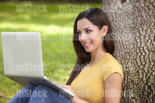 Joven feliz trabajando en computadora en el parque