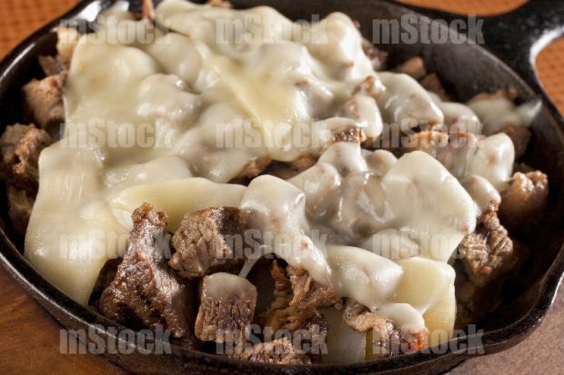 Carne asada con queso al gratin en plato caliente